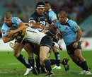 Waratahs wing Drew Mitchell feels the force of the Brumbies' defence