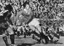 Barry John slips past an All Black tackle