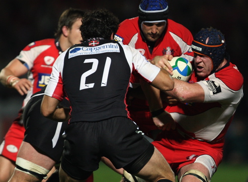 Peter Buxton of Gloucester is tackled by Jacques Cronje and Andre Masi of Biarritz