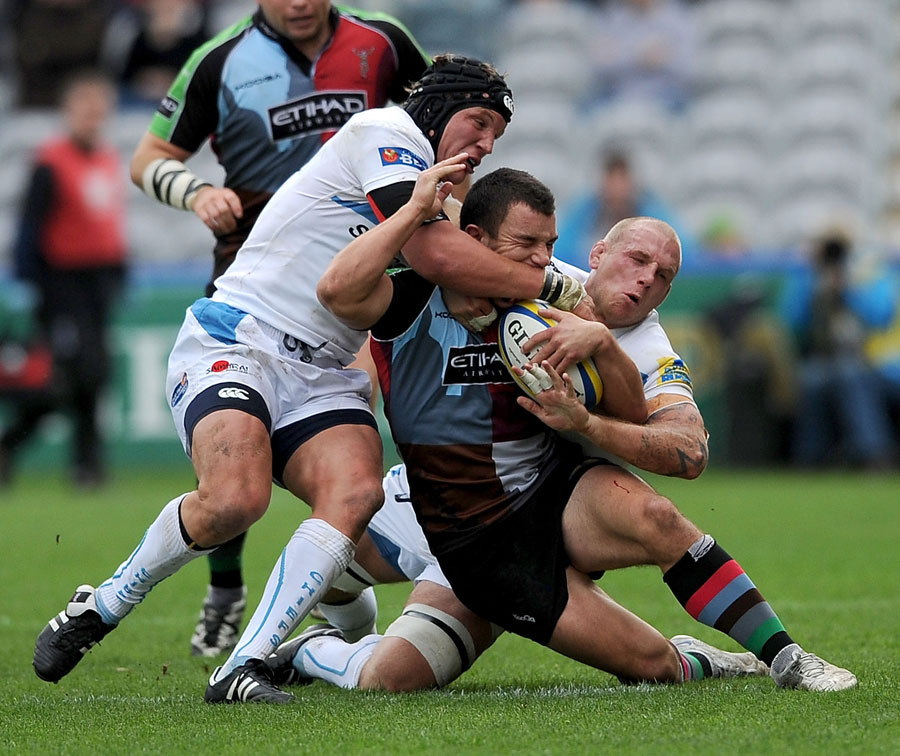 Harlequins' George Lowe is taken down by Tom Johnson and James Scaysbrook
