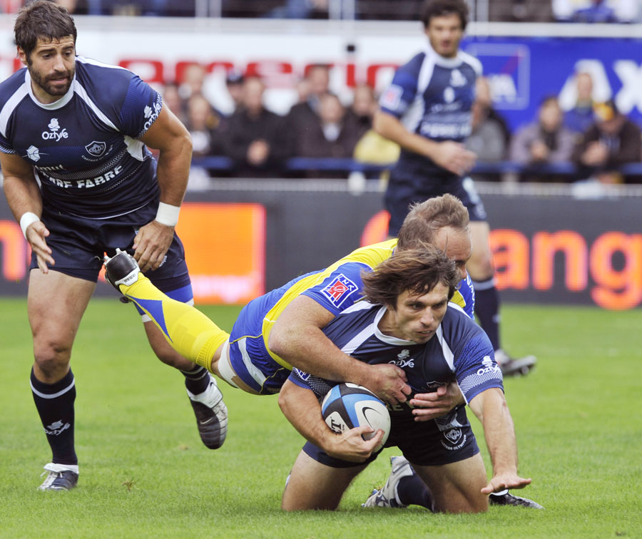 Castres fullback Romain Teulet is tackled by Marius Joubert