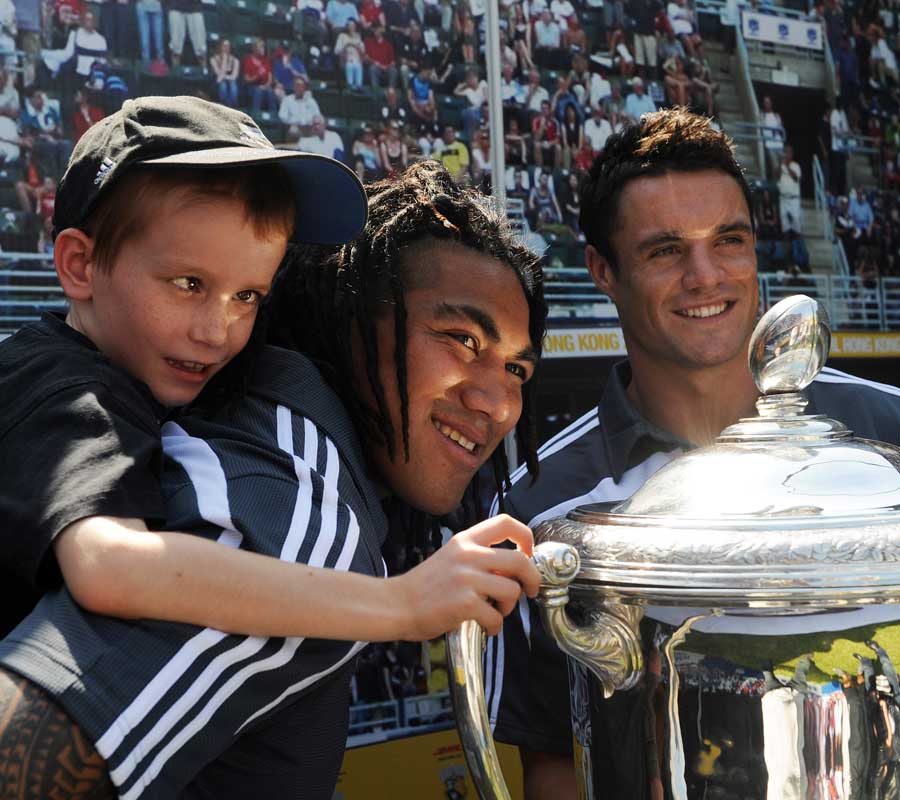 Ma'a Nonu hoists a young fan on his back as Dan Carter poses with the Bledisloe Cup in Hong Kong