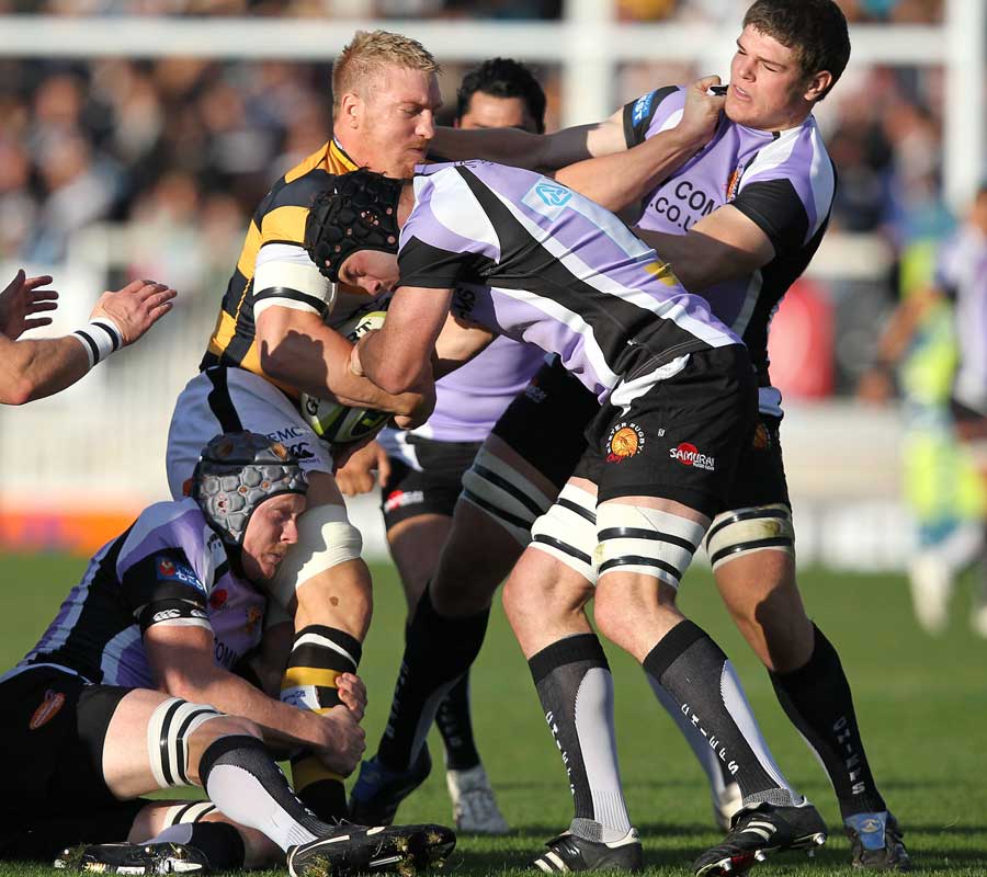Andy Powell is tackled by Exeter's Peter Kimlin and Dave Gannon