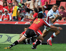 Reds fly-half Quade Cooper evades a tackle from Lions centre Doppies La Grange