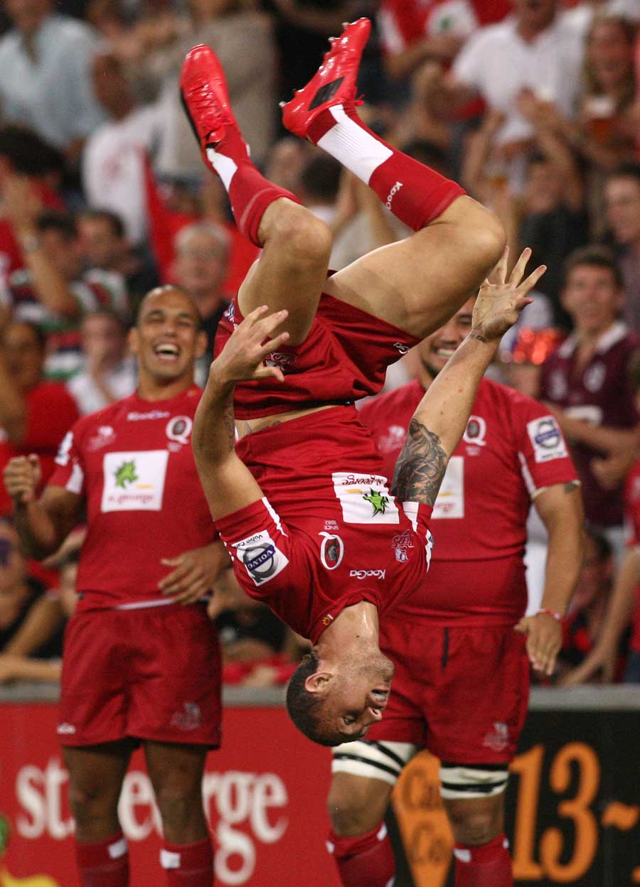 The Reds' Quade Cooper goes airbourne to celebrate a try
