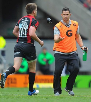Saracens coach Andy Farrell tosses a kicking tee to son Owen