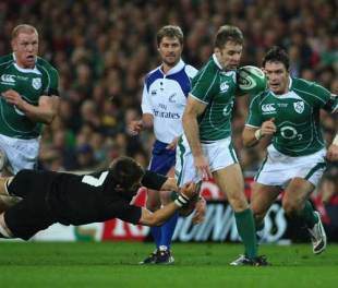 Tomas O'Leary of Ireland is tackled by Richie McCaw of New Zealand while referee Mark Lawrence looks on during the match between Ireland and the New Zealand All Blacks at Croke Park in Dublin, Ireland on November 15, 2008.