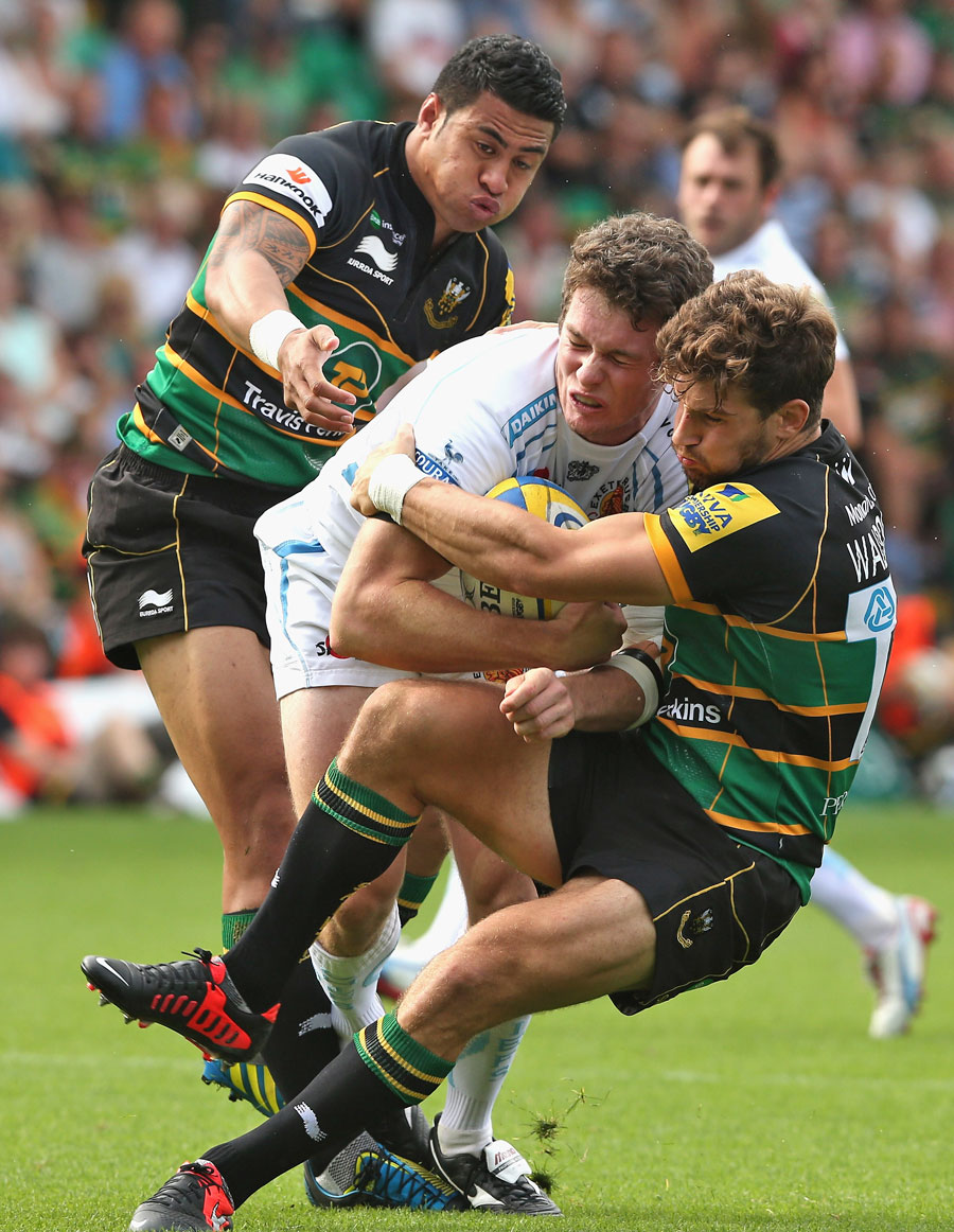 Exeter's Ian Whitten is tackled by Northampton's George Pisi and Dominic Waldouck