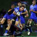 Nick Cummins of the Western Force is tackled by Aaron Cruden