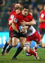 The Crusaders' Dan Carter breaks a tackle from the Reds' Ed Quirk