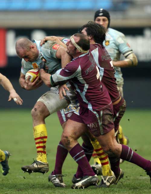 Perpignan's lock Olivier Olibeau (L) looks to break the tackle of Bourgoin lock Camille Levast