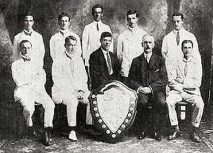 The first committee of the Fiji Rugby Football Union, photographed on the occasion of the presentation of the Escott Shield in 1913. Seated directly behind the shield is PJ " Paddy" Sheehan, beside him in the other dark suit is then Governor, Sir Ernest Bickham Sweet-Escott