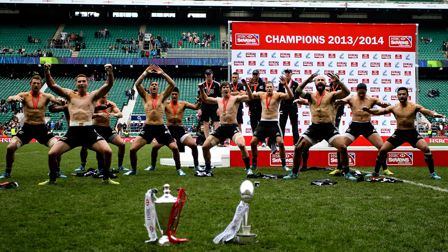 The victorious New Zealanders perform a Haka in front of the two trophies 