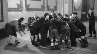 Boys playing rugby in the former ballroom of the fashionable Wellington Rooms. Stella Baker, warden of the Rodney Youth Centre, plays scrum-half, London, March 5, 1949 
