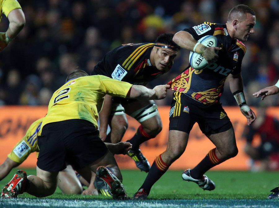 Aaron Cruden of the Chiefs breaks the tackle of Dane Coles of the Hurricanes 
