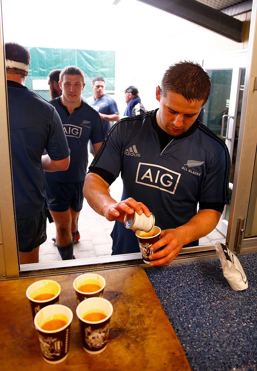 New Zealand's Dane Coles takes a cup of hot soup following a wet All Blacks training session