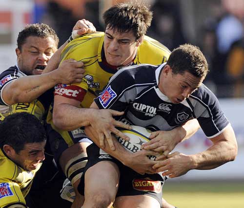 Castres'  fly-half Cameron MacIntyre is tackled by two Clermont players 