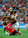 Aaron Cruden of the Chiefs leaps over the tackle of Mitchell Drummond of the Crusaders