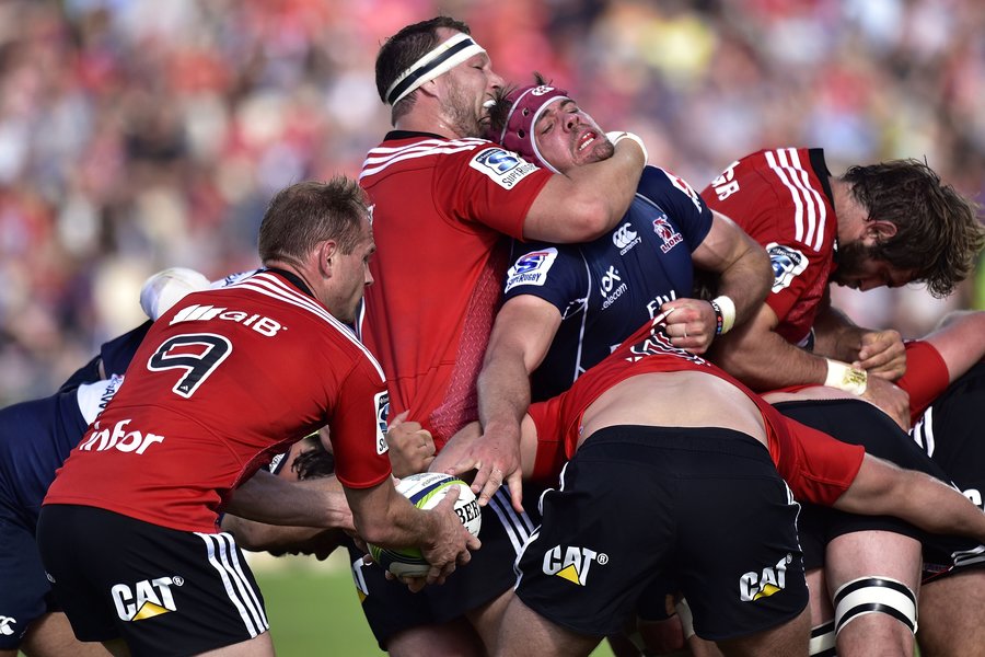 Lions' captain Warren Whiteley is restrained by Crusaders' Wyatt Crockett as Crusaders' Andy Ellis collects the ball from the back of a maul