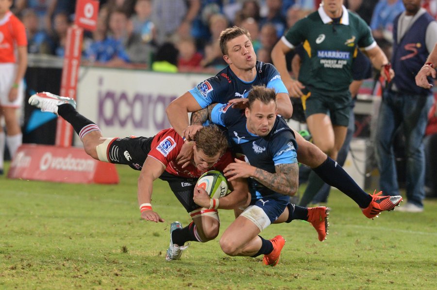 Andries Coetzee of the Lions tackled by Handre Pollard and Francois Hougaard of the Bulls