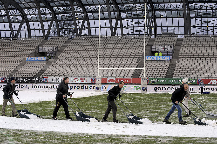 Ground staff attempt to clear the snow from the Stade des Alpes