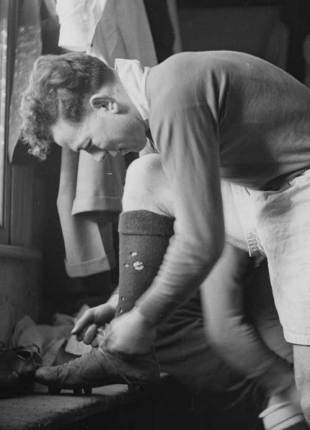 Ireland hooker Karl Mullen ties his boots in the changing room, March 17, 1951