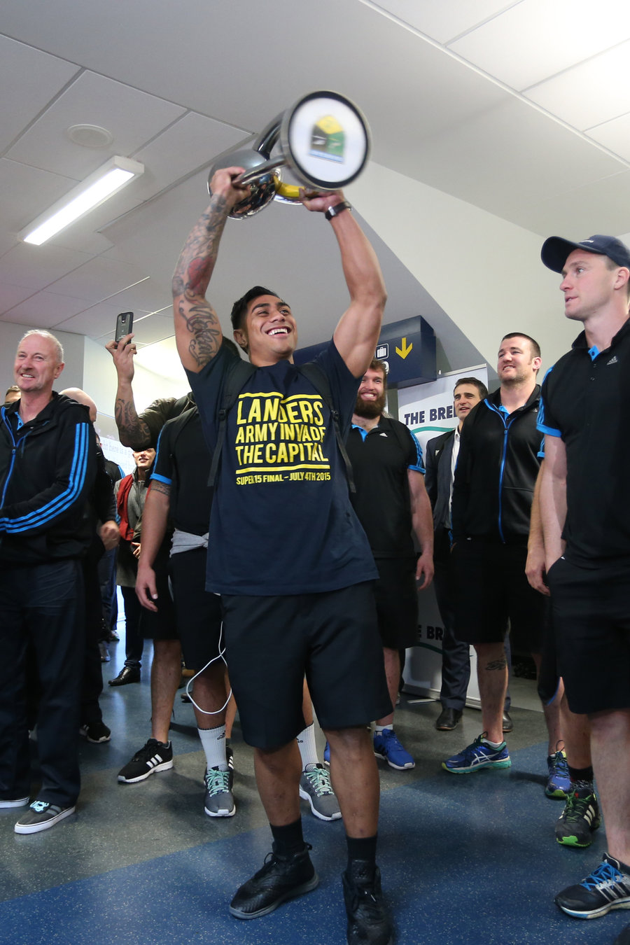 Malakai Fekitoa holds the Super Rugby trophy aloft upon arrival at Dunedin Airport