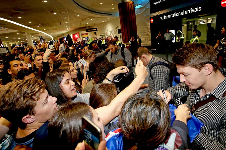 New Zealand's Beauden Barrett and the All Black signs autographs after arriving home