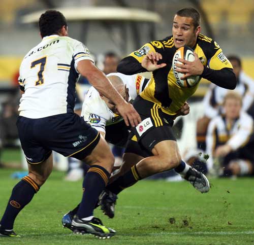 The Hurricanes' Tamati Ellison fends off the Brumbies' George Smith