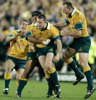 Matthew Burke of the Wallabies celebrates with team mates Toutai Kefu and Stirling Mortlock after kicking the winning penalty kick after the final siren of the Tri Nations Rugby Union test match between Australia and New Zealand played at Telstra Stadium in Sydney, Australia on August 3, 2002