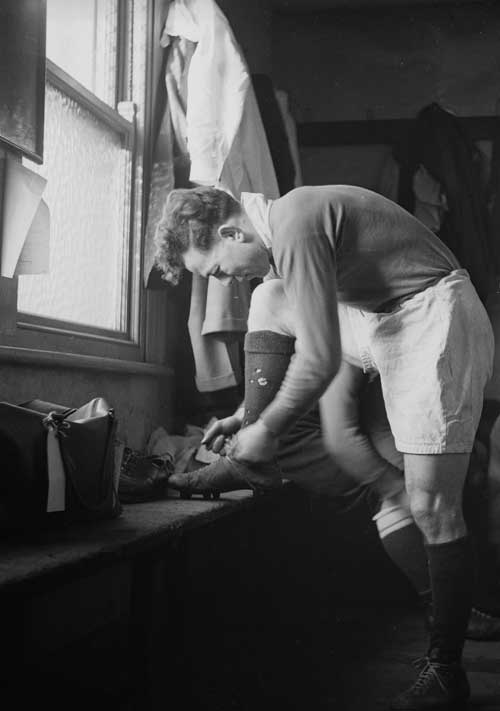 Irish rugby player Karl Mullen tying his boot laces in the changing room
