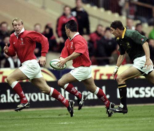Shane Howarth carries the ball, waiting to offload to Gareth Thomas