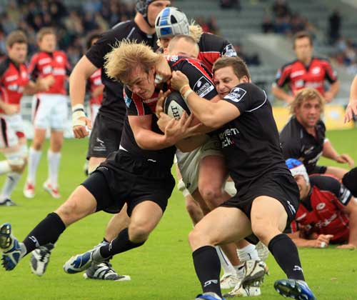 Saracens' Rhys Gill is tackled by Newcastle's Jimmy Gopperth and Hall Charlton