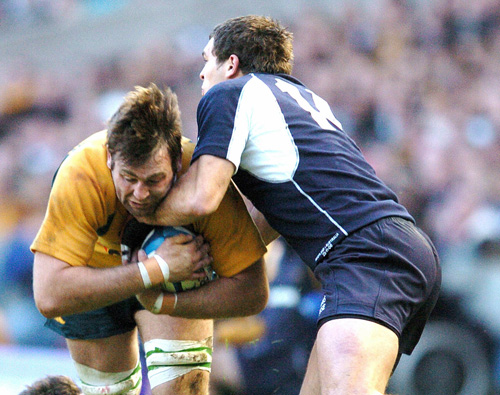Australia No.8 David Lyons is tackled by the Scottish defence