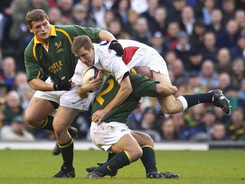 Will Greenwood is tackled by South Africa's James Dalton and Deon Carstens 