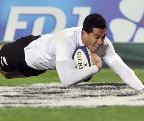 New Zealand's Mils Muliaina dives over to score
