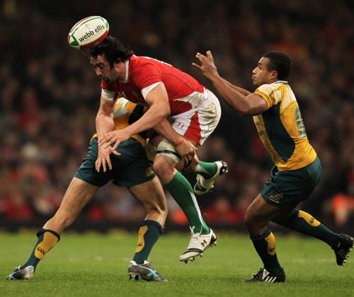 Wales flanker Jonathan Thomas is upended by Quade Cooper