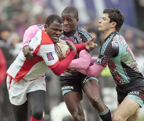 Biarritz's Takudzwa Ngwenya is tackled by Stade Francais' Djibril Camara and Guillaume Bousset