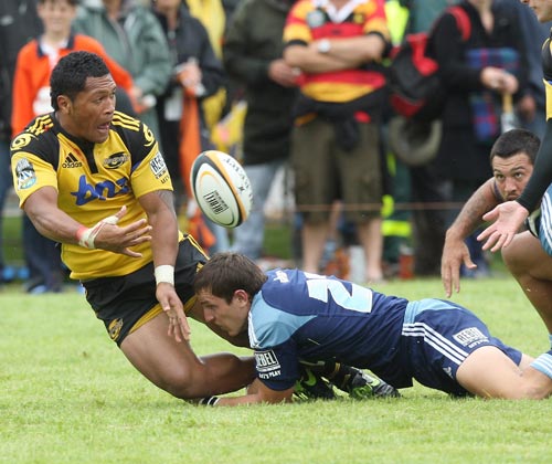 The Hurricanes' Johnny Leota is tackled by the Blues' Michael Harris