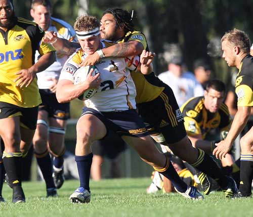 The Brumbies' Michael Hooper is tackled by the Hurricanes Ma'a Nonu