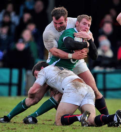Ireland A's Denis Hurley is wrapped up by the England Saxons defence