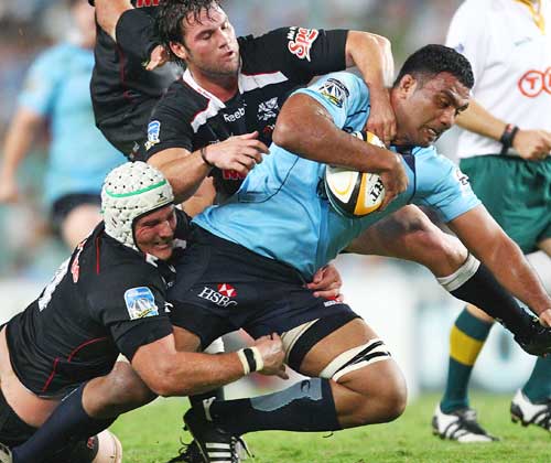 The Waratahs' Wycliff Palu stretches the Sharks' defence