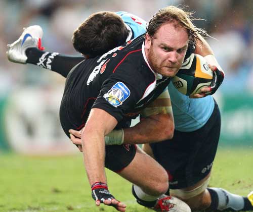 Sharks' fly-half Andy Goode is tackled by the Waratahs' defence